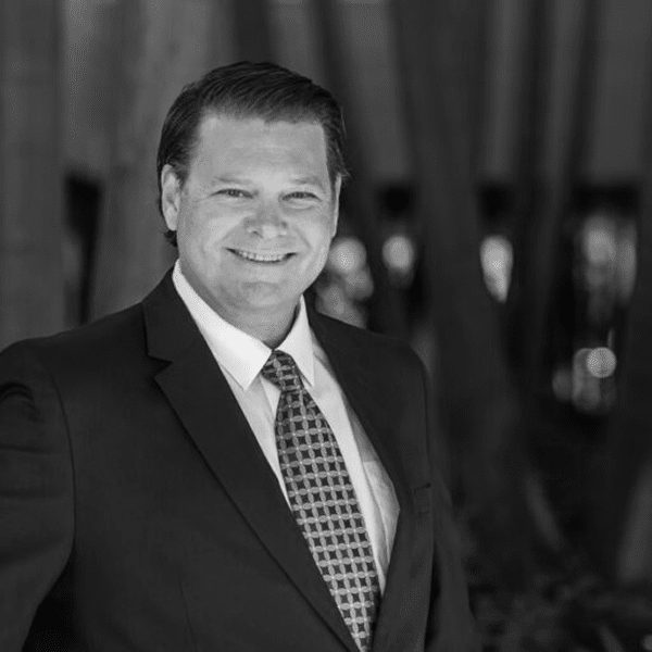 Black and white portrait of a man in a suit smiling.