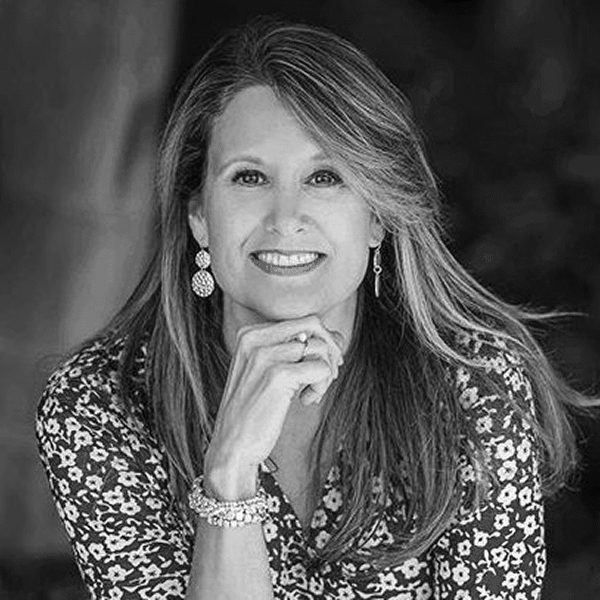 Smiling woman with long hair poses in black and white photo.