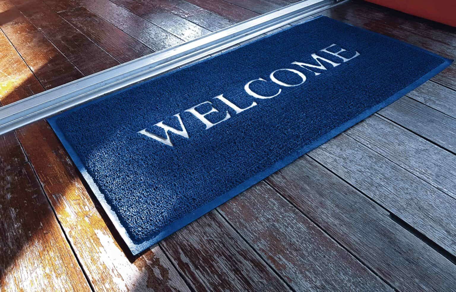 Blue welcome mat on wooden floor.